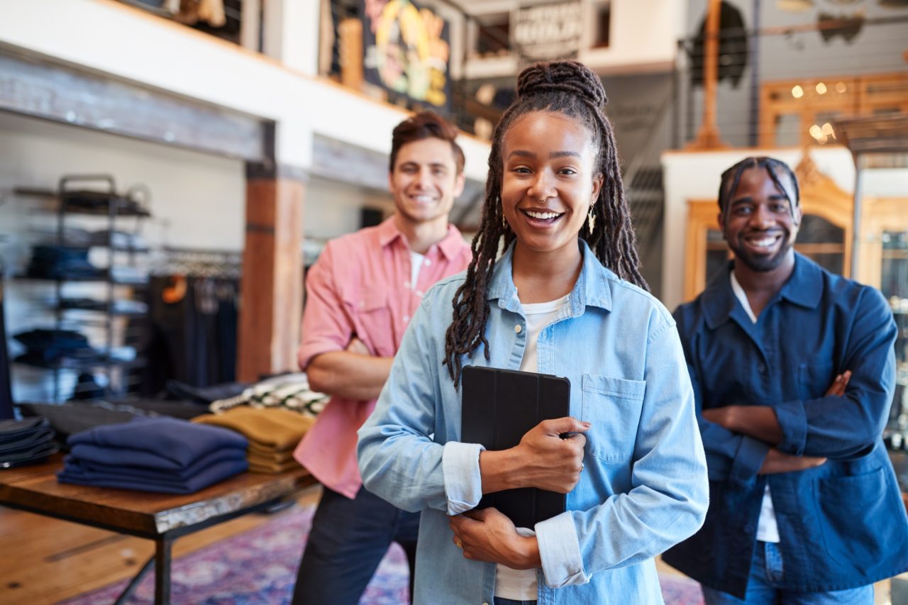 portrait of smiling multi cultural sales team in fashion store in front of clothing display.jpg